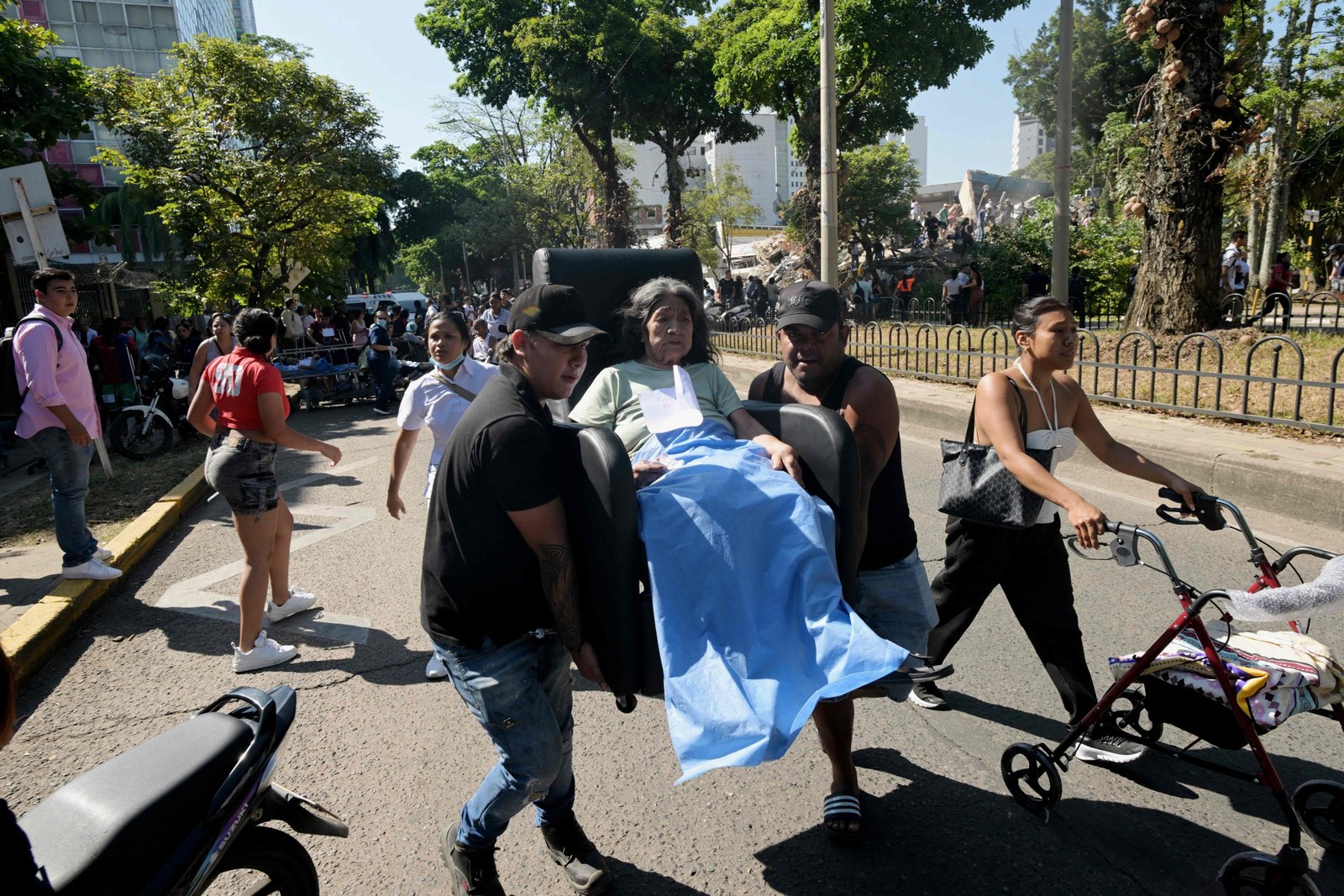 Uma mulher idosa é carregada sobre um móvel perto de um edifício desabado após um terremoto em Cali — Foto: JOAQUIN SARMIENTO / AFP