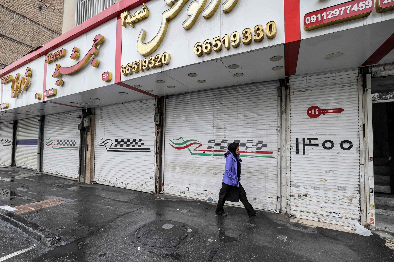 Mulher passa por lojas fechadas ao longo da rua Satarkhan, na capital do Irã, Teerã — Foto: ATTA KENARE/AFP