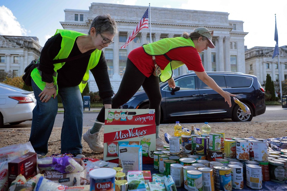 Voluntários organizam doações de feijão, leite em pó e outros itens não perecíveis durante uma campanha de arrecadação de alimentos em frente ao Departamento de Agricultura dos EUA, em Washington — Foto: Chip Somodevilla/Getty Images/AFP