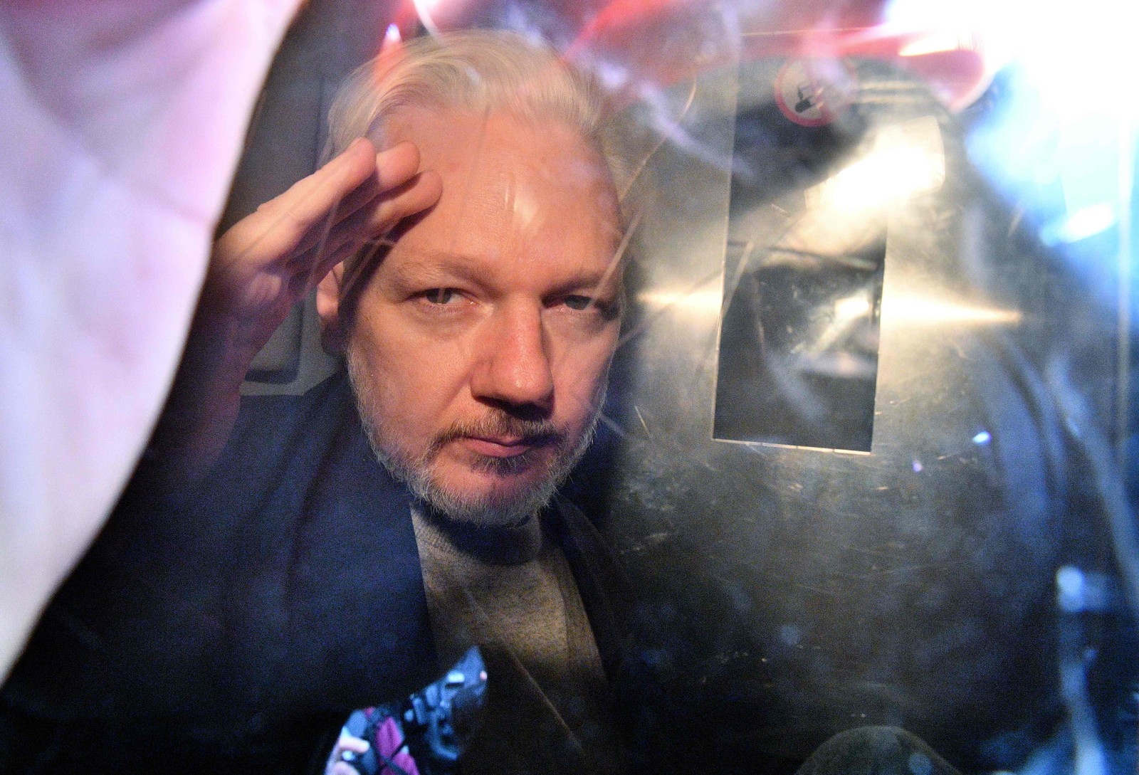 O fundador do WikiLeaks, Julian Assange, gesticula da janela de uma van da prisão enquanto é expulso do Southwark Crown Court, em Londres, em maio de 2019, após ter sido condenado a 50 semanas de prisão por violar suas condições de fiança em 2012. — Foto: Daniel LEAL-OLIVAS/AFP