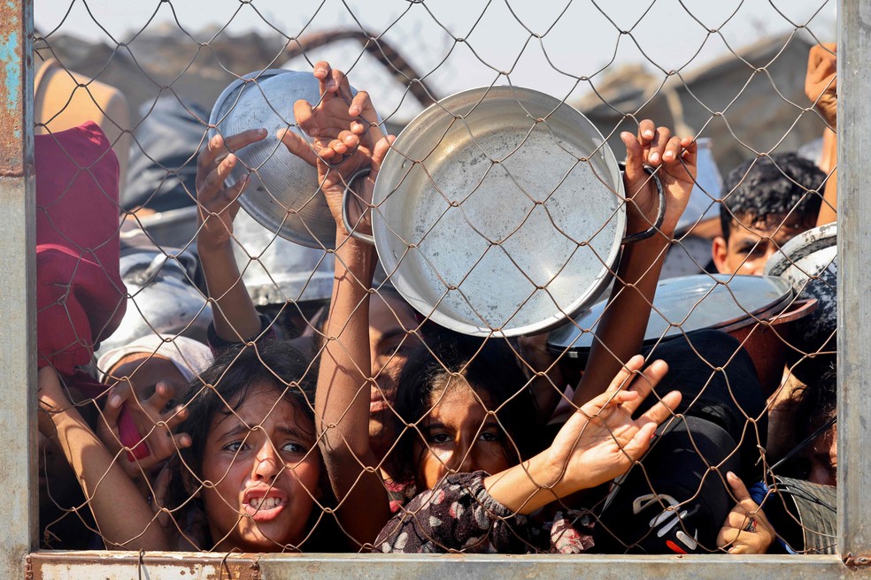 Crianças palestinas imploram por comida em área de ajuda humanitária próxima a Khan Younis, na Faixa de Gaza, em 22 de julho de 2025 — Foto: AFP