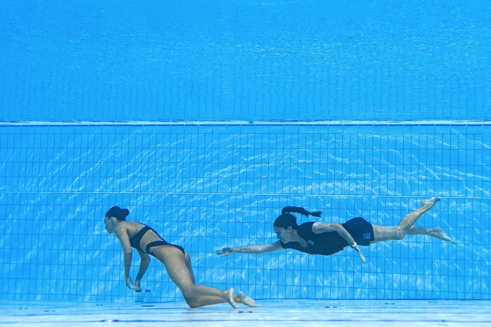 A treinadora dos EUA Andrea Fuentes nada para socorrer a atleta norte-americana Anita Alvarez no fundo da piscina durante um incidente na final de natação artística livre solo feminino do Campeonato Mundial de Esportes Aquáticos de Budapeste, em 22 de junho — Foto: Oli SCARFF / AFP