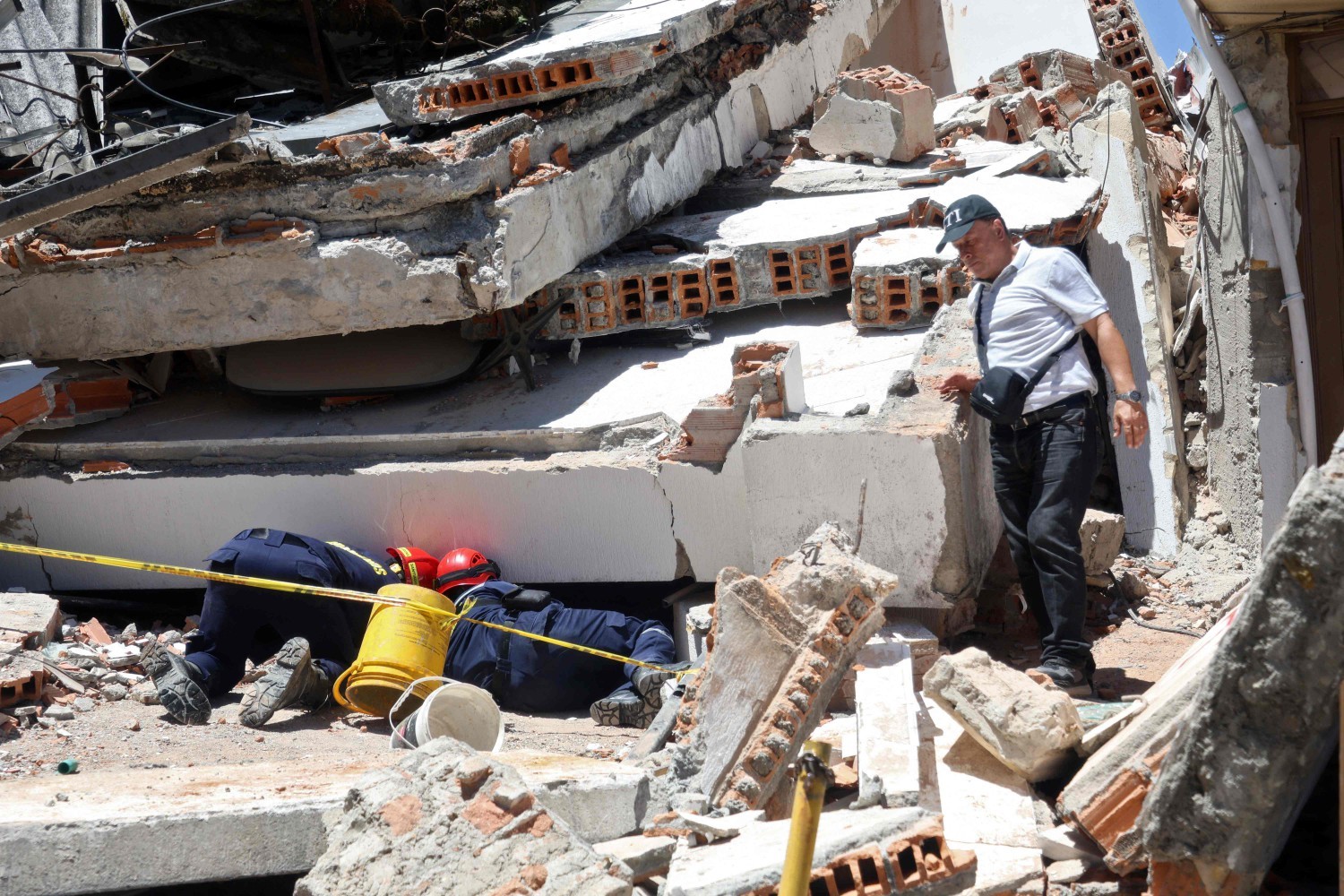 Resgatistas procuram por sobreviventes em um edifício desabado após o terremoto em Manizales, Colômbia. — Foto: Giovanny Galvez / AFP