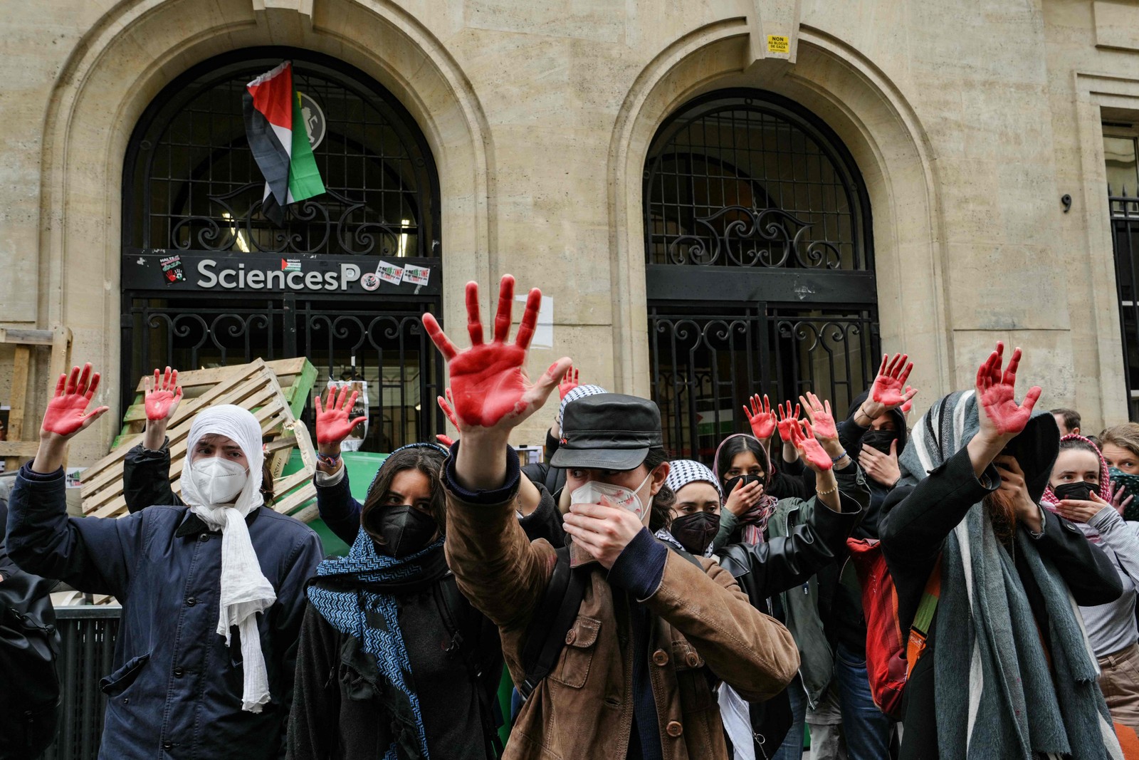 Os manifestantes levantam as mãos cobertas de tinta vermelha para simbolizar o sangue enquanto participam de uma manifestação em frente ao Instituto de Estudos Políticos (Sciences Po Paris) ocupado por estudantes, em apoio aos palestinos, em Paris — Foto: Dimitar DILKOFF / AFP