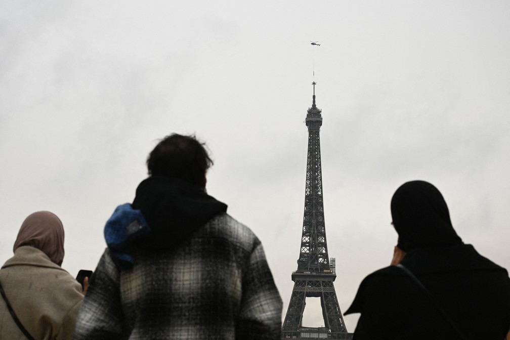 Pedestres olham a nova antena que deixou a Torre Eiffel em Paris mais alta — Foto: Emmanuel Dunand / AFP