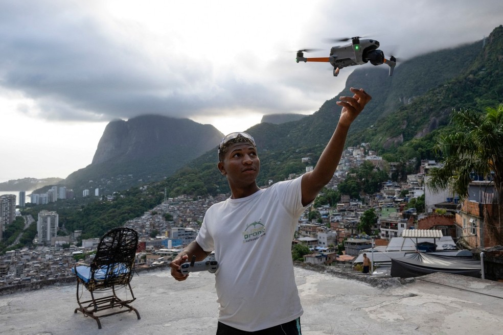 O piloto de drone brasileiro Pedro Lucas recolhe seu drone após filmar uma turista para um vídeo nas redes sociais no famoso mirante turístico “Porta do Céu”, na favela da Rocinha, no Rio de Janeiro. — Foto: Pablo Porciúncula/AFP