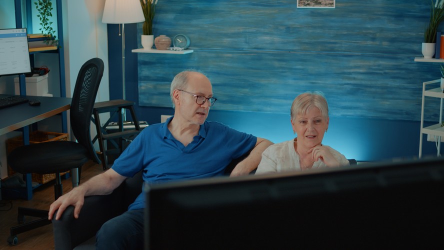 Casal de idosos assiste TV.