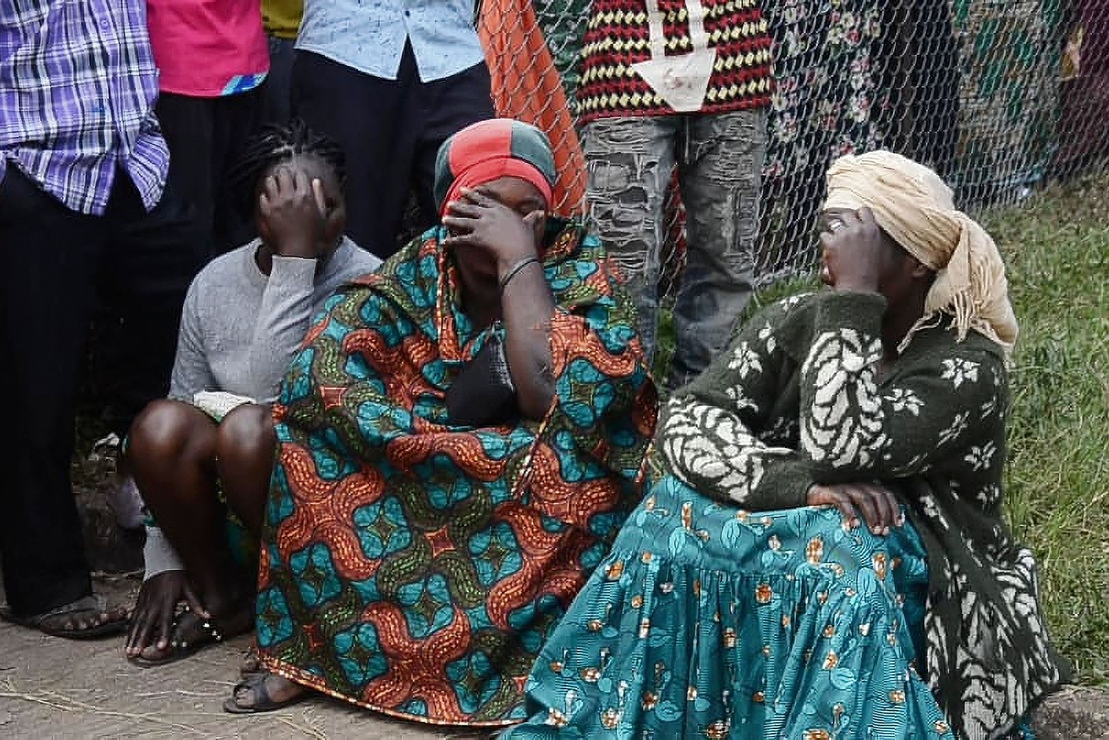 Pessoas lamentam mortes de jovens após grupo ligado ao Estado Islâmico atacar escola em Uganda e deixar dezenas de mortos — Foto: AFP