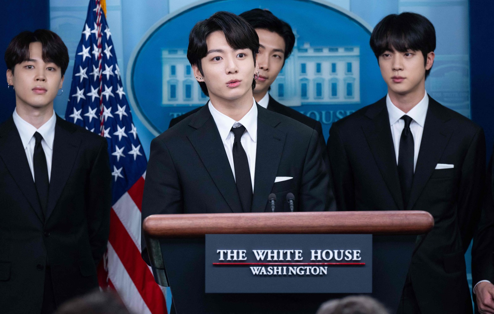 Jungkook, membro mais novo do BTS, discursa na Casa Branca em 31 de maio de 2022. Atrás dele, aparecem Jimin, RM e Jin. — Foto: SAUL LOEB / AFP