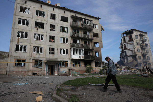 Um residente local passa por prédios de apartamentos destruídos por uma bomba aérea na vila de Ocheretyne, não muito longe da cidade de Avdiivka, na região de Donetsk,  em meio à invasão russa na Ucrânia.