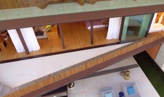 Varanda de um dos andares da mansão e piscina que vai da varanda à sala