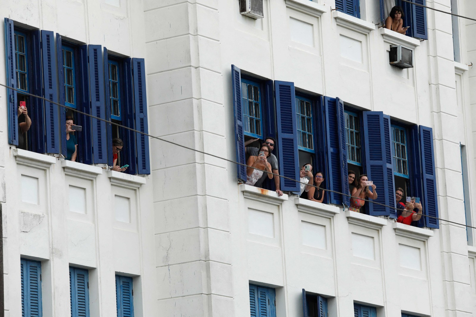 Fãs registram das janelas dos prédios a passagem do cortejo com o corpo do rei — Foto: CAIO GUATELLI / AFP