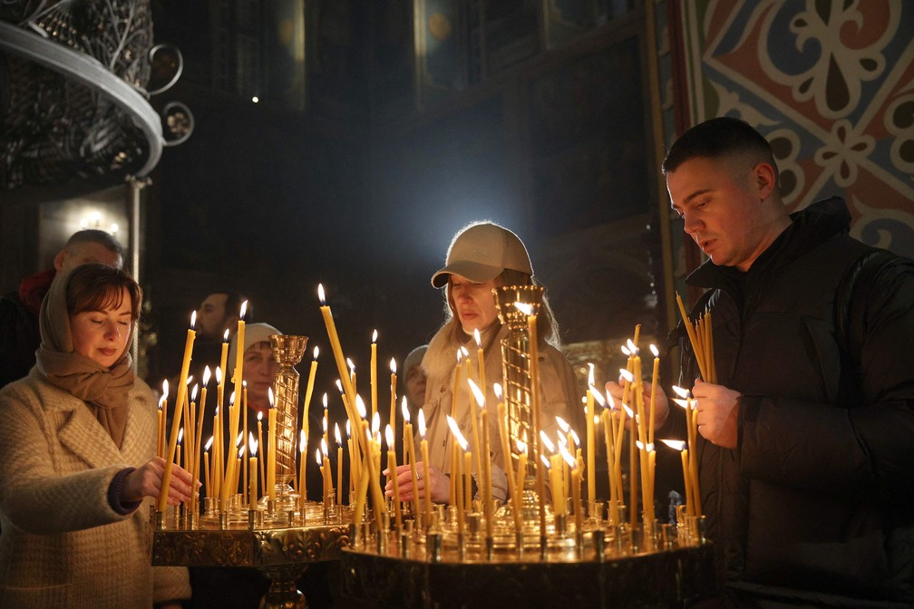 Fiéis acendem velas durante um culto de Natal na Catedral de São Miguel em Kiev, na Ucrânia — Foto: AFP/ Anatolii Stepanov