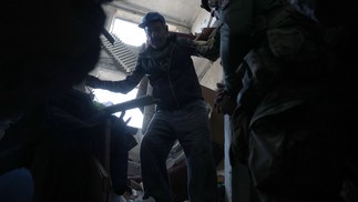 Um political, Dmytro Solovyi (direita), fala com o morador local Yuriy, 70 anos, enquanto trabalha para retirar o corpo da esposa do morador dos escombros depois que ela foi morta por bombardeio em Ocheretyne — Foto: Anatolii STEPANOV/AFP