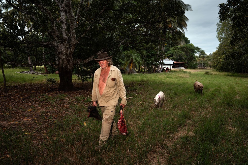 Trevor Sullivan sai para alimentar alguns dos 13 crocodilos de estimação em sua extensa propriedade em Darwin River — Foto: Matthew Abbott / The New York Times