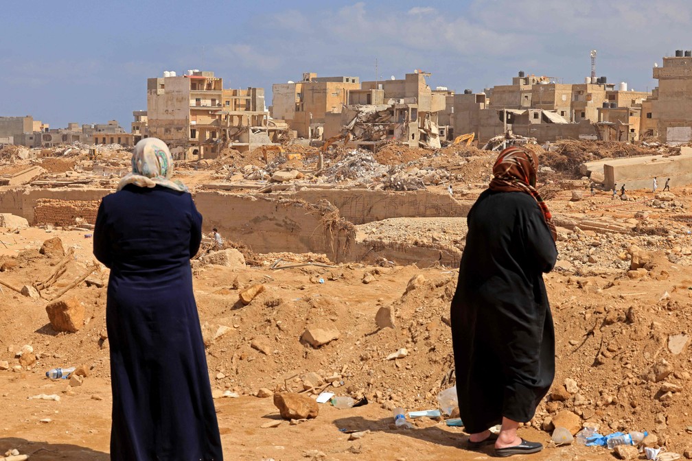 Sobreviventes olham para os escombros de edifícios destruídos na cidade de Derna, no leste da Líbia — Foto: KARIM SAHIB/AFP