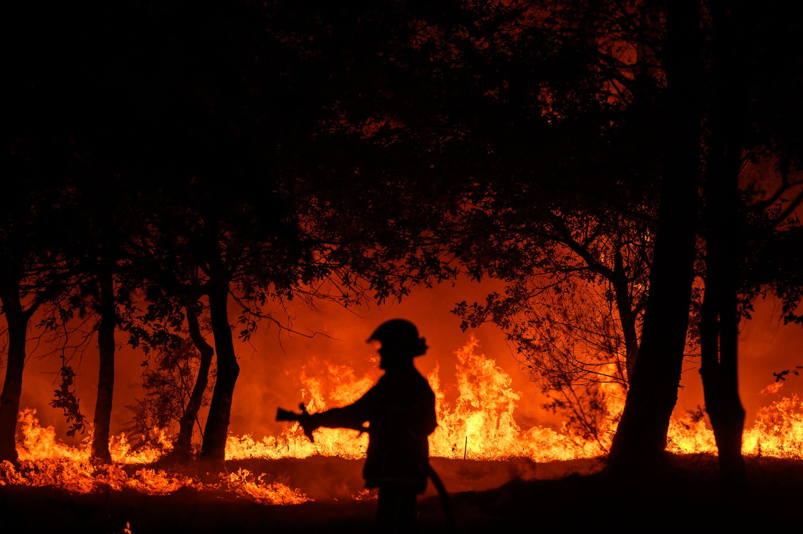 Bombeiro combate incêndio noturno em Saumos, perto de Bordeaux, sudoeste da França, onde moradores precisaram ser evacuados  — Foto: PHILIPPE LOPEZ / AFP