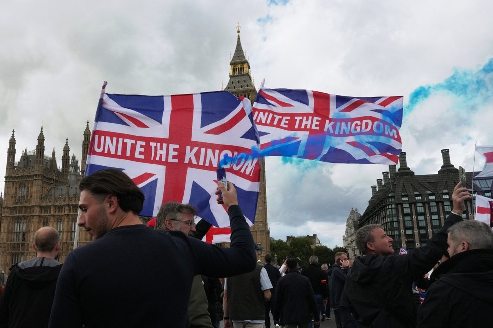 Apoiadores do ativista britânico de extrema direita Tommy Robinson marcham com bandeiras da Grã-Bretanha perto do Parlamento, no centro de Londres, durante uma manifestação anti-imigração — Foto: CARLOS JASSO/AFP