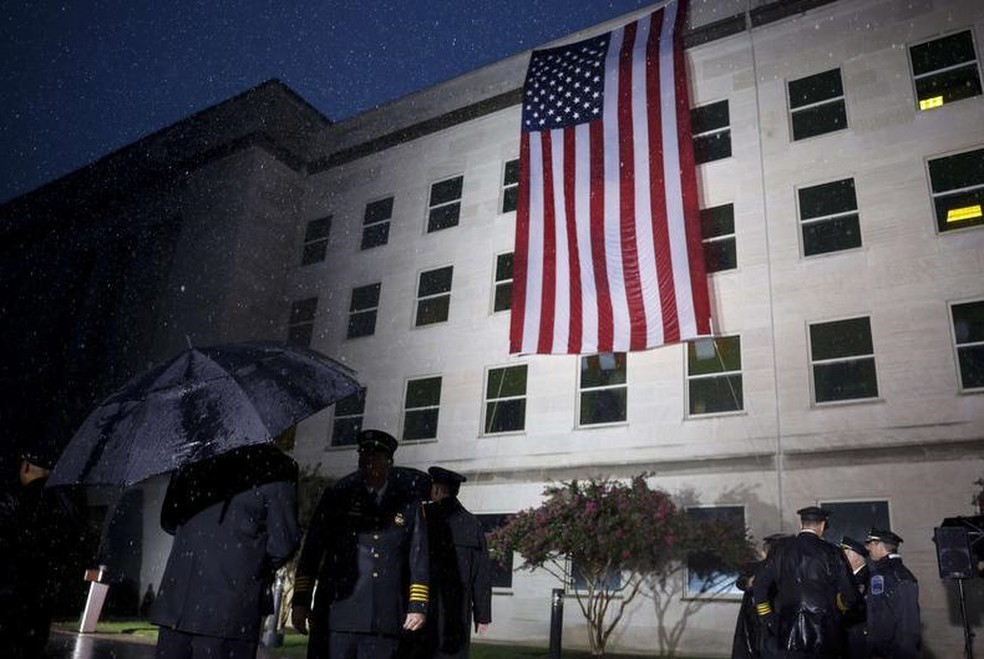 Membros das forças armadas e socorristas fazem continência enquanto uma bandeira americana é estendida ao lado do Pentágono para comemorar o 21º aniversário dos ataques terroristas de 11 de setembro — Foto: AFP