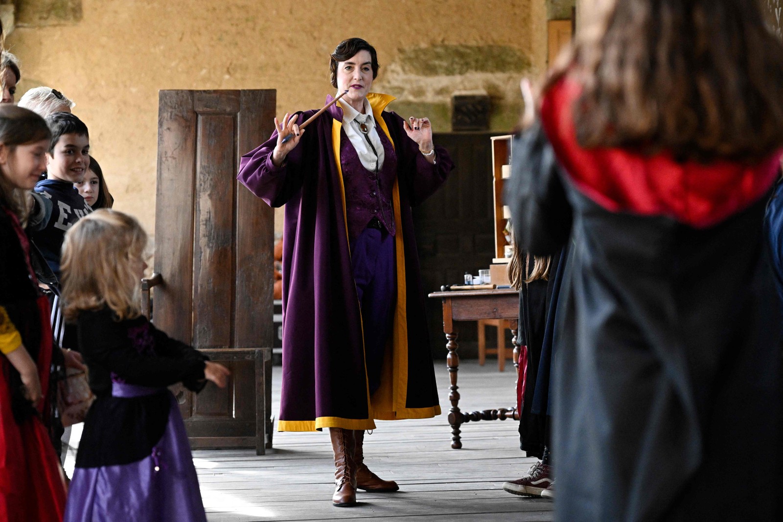 Pequenos visitantes observam um ator que interpreta um professor na "escola de bruxaria" montada no Château Le Rocher-Portail, na França — Foto: Damien Meyer/ AFP
