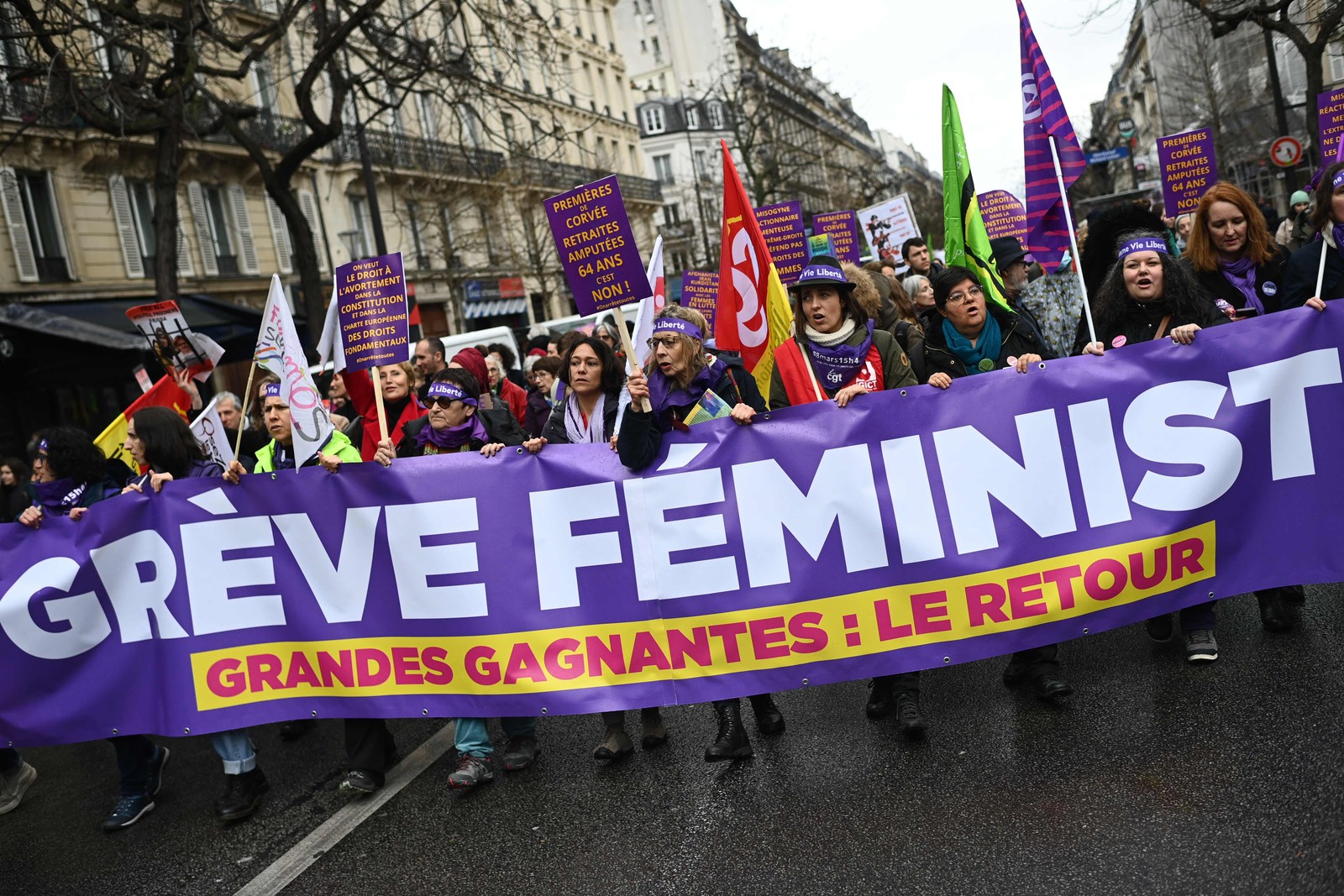 Mulheres marcham atrás de uma faixa com os dizeres "Greve feminista" enquanto participam de uma manifestação para marcar o Dia Internacional da Mulher em Paris, em 8 de março de 2023. Christophe Archambault / AFP