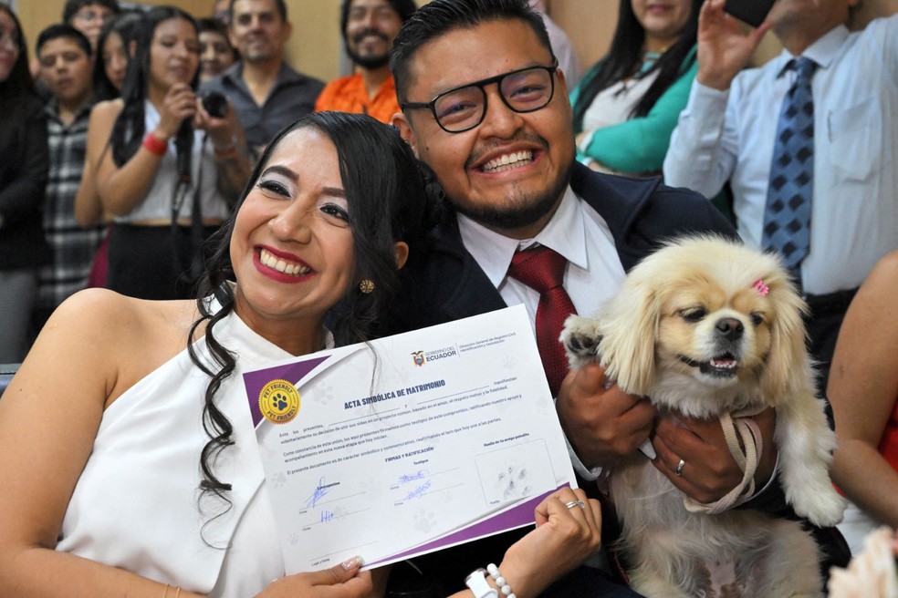 Andrés Alquinga e Diana Tupiza colocam a pegada de sua cadela de estimação, Luna, como testemunha simbólica de seu casamento no cartório central de registro civil em Quito — Foto: RODRIGO BUENDIA/AFP