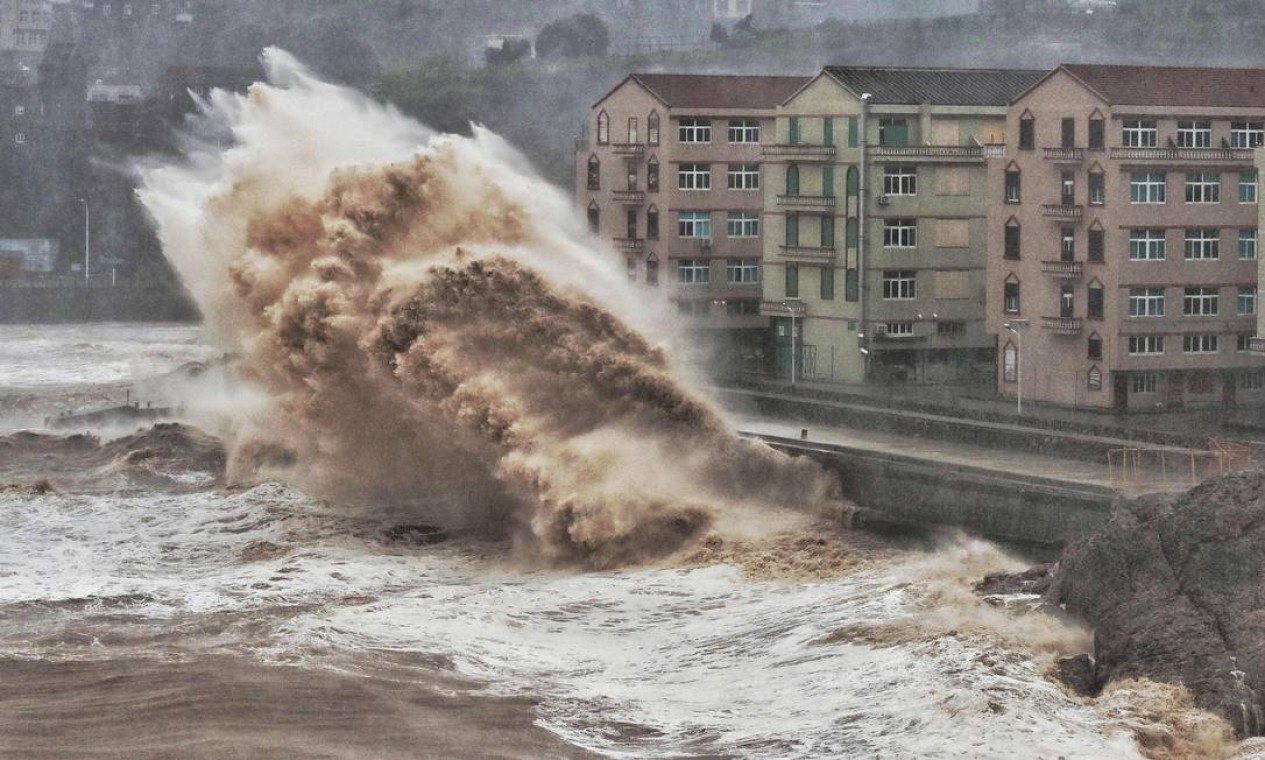 Ondas atingem um paredão em frente a edifícios em Taizhou, província de Zhejiang, leste da China. Os mesmos oceanos que nutriram a evolução humana estão prontos para desencadear a miséria em escala global alerta um projeto de relatório da ONU — Foto: AFP