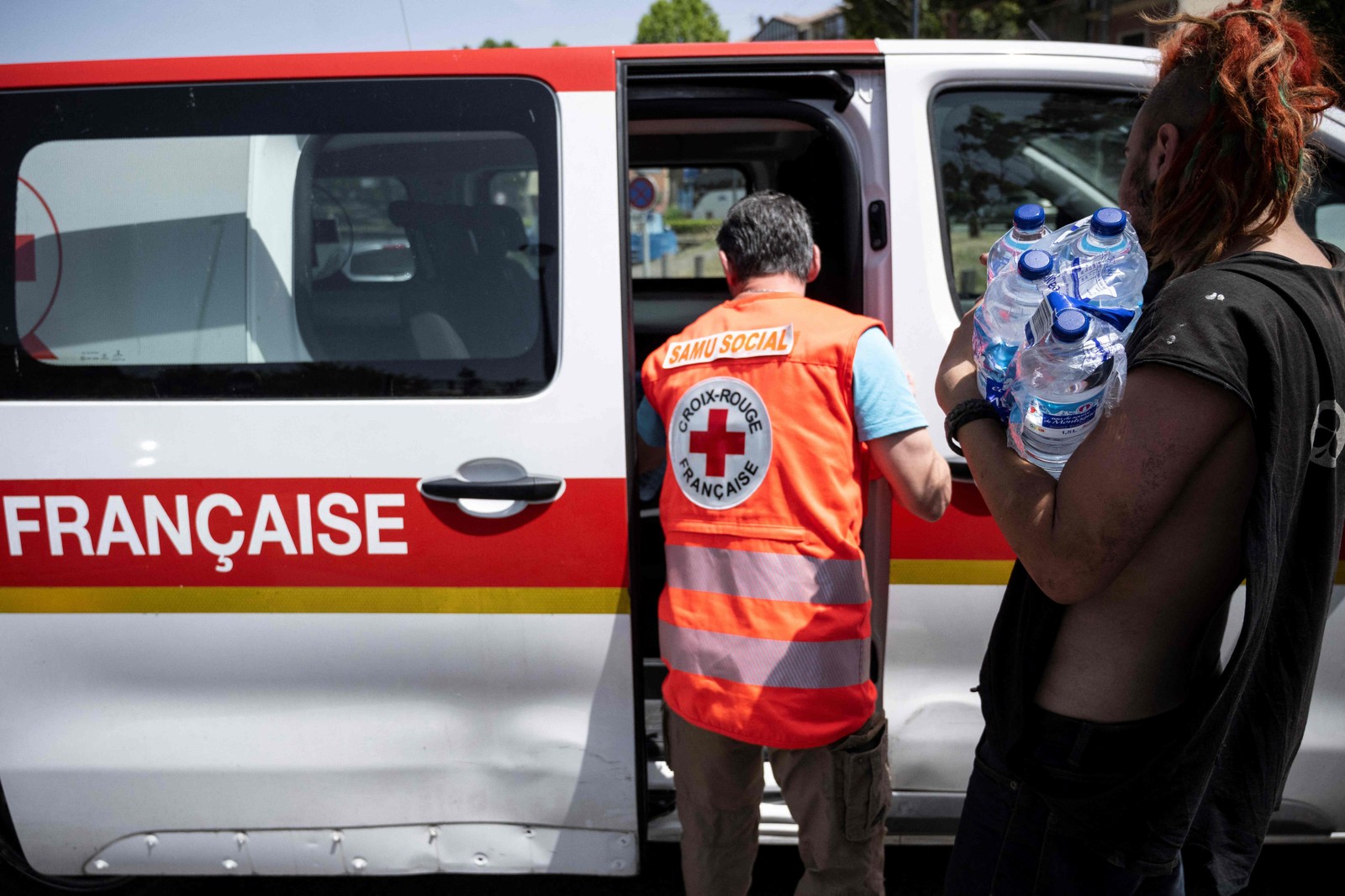 Membro da equipe da Cruz Vermelha Francesa distribui água engarrafada fresca para os sem-teto em Toulouse, sudoeste da França. — Foto: Lionel BONAVENTURE/AFP